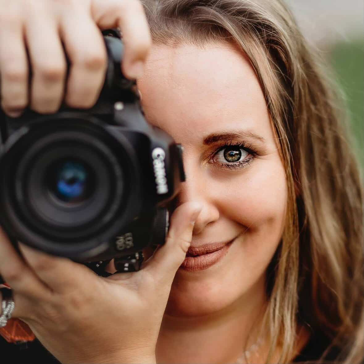 Mel holding her camera with a warm smile